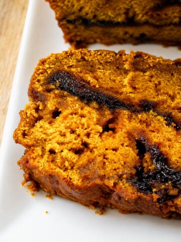 Two thick slices of pumpkin butterscotch swirl bread on a white plate.