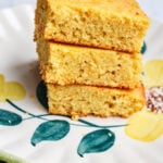 A stack of three square pieces of grandmother's buttermilk cornbread on a floral plate.