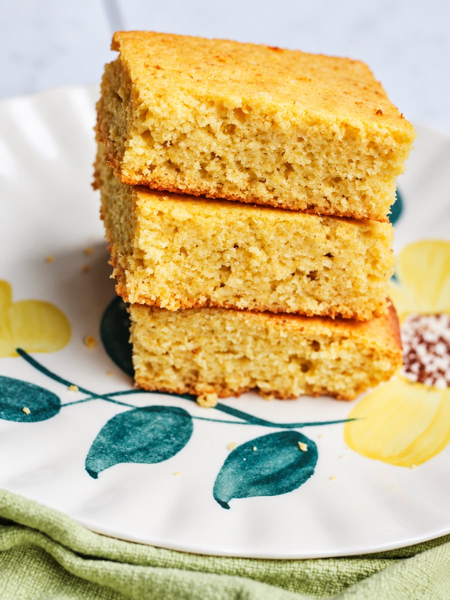 A stack of three square pieces of grandmother's buttermilk cornbread on a floral plate.