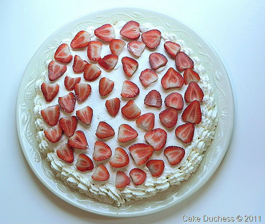 overhead image of cake with strawberries and whipped cream on top