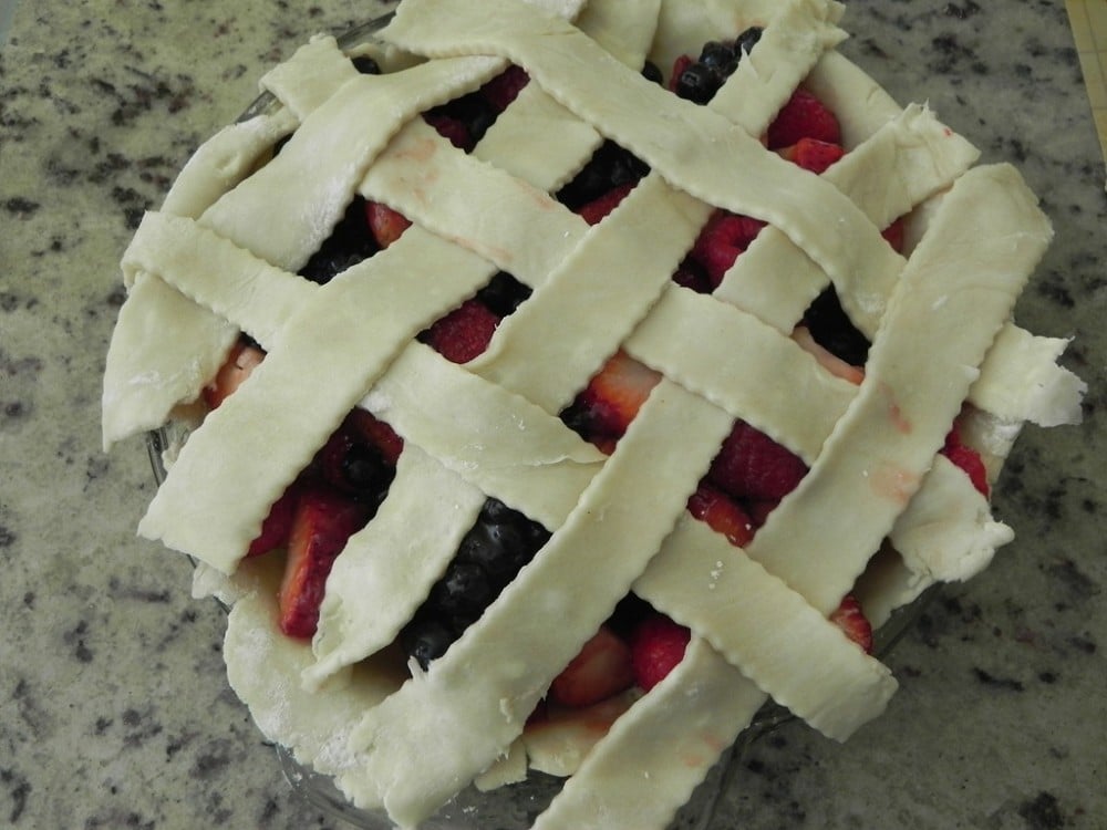 overhead image of lattice strips over a pomegranate mixed berry pie