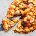 A flaky Autumn Crostata with fruit filling, with one slice being lifted by a metal spatula.