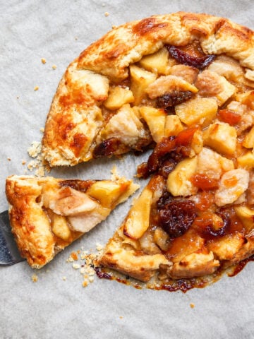 A flaky Autumn Crostata with fruit filling, with one slice being lifted by a metal spatula.