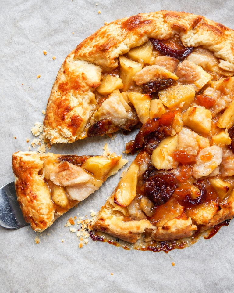 A flaky Autumn Crostata with fruit filling, with one slice being lifted by a metal spatula.