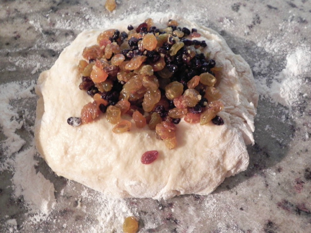 overhead image of dough on counter with dried fruits on top