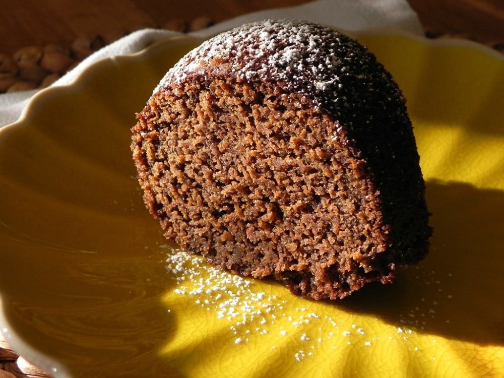 overhead image of slice of vegan black sticky gingerbread on a yellow plate