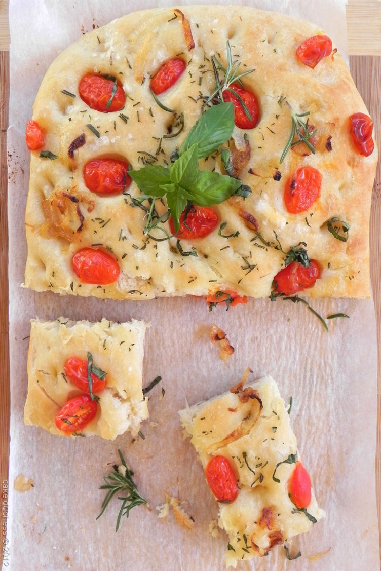 overhead image of bread topped with herbs and tomatoes