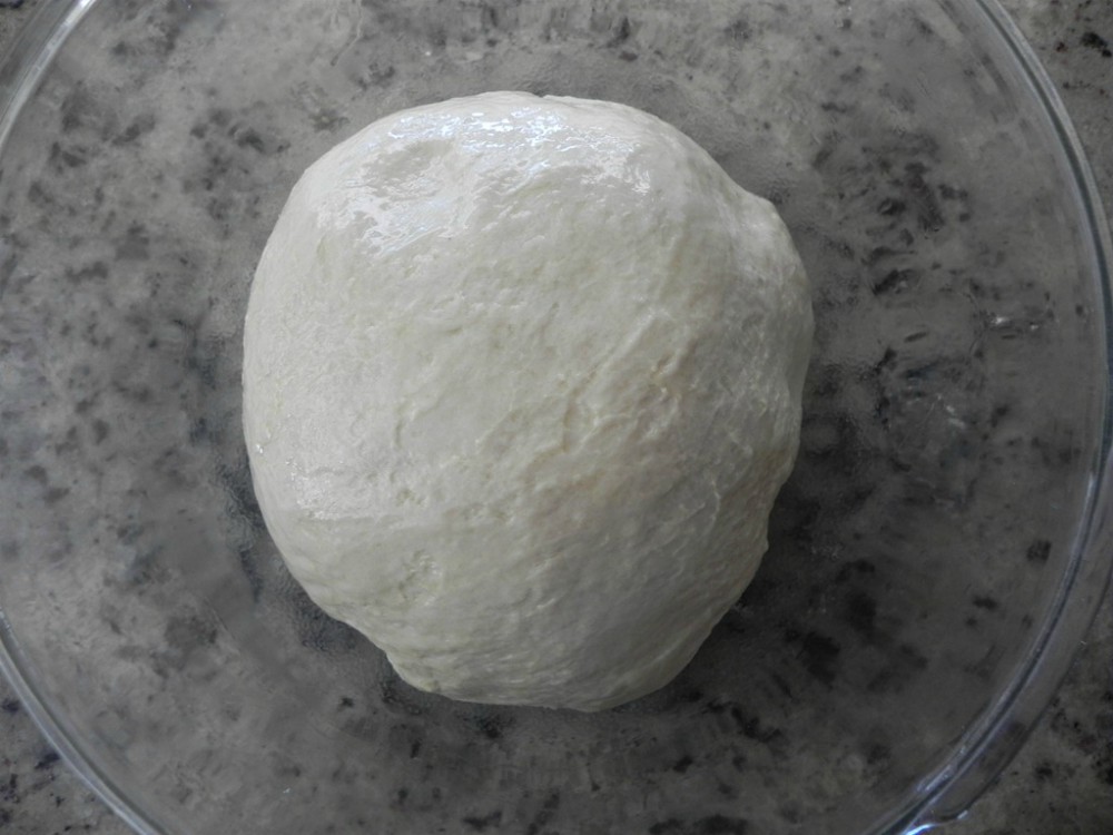 overhead image of a ball of dough in a glass bowl