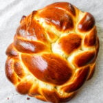 Golden braided honey challah bread on a parchment lined baking sheet