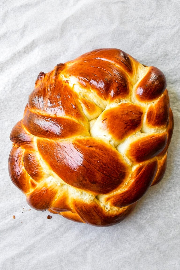 Golden braided honey challah bread on a parchment lined baking sheet