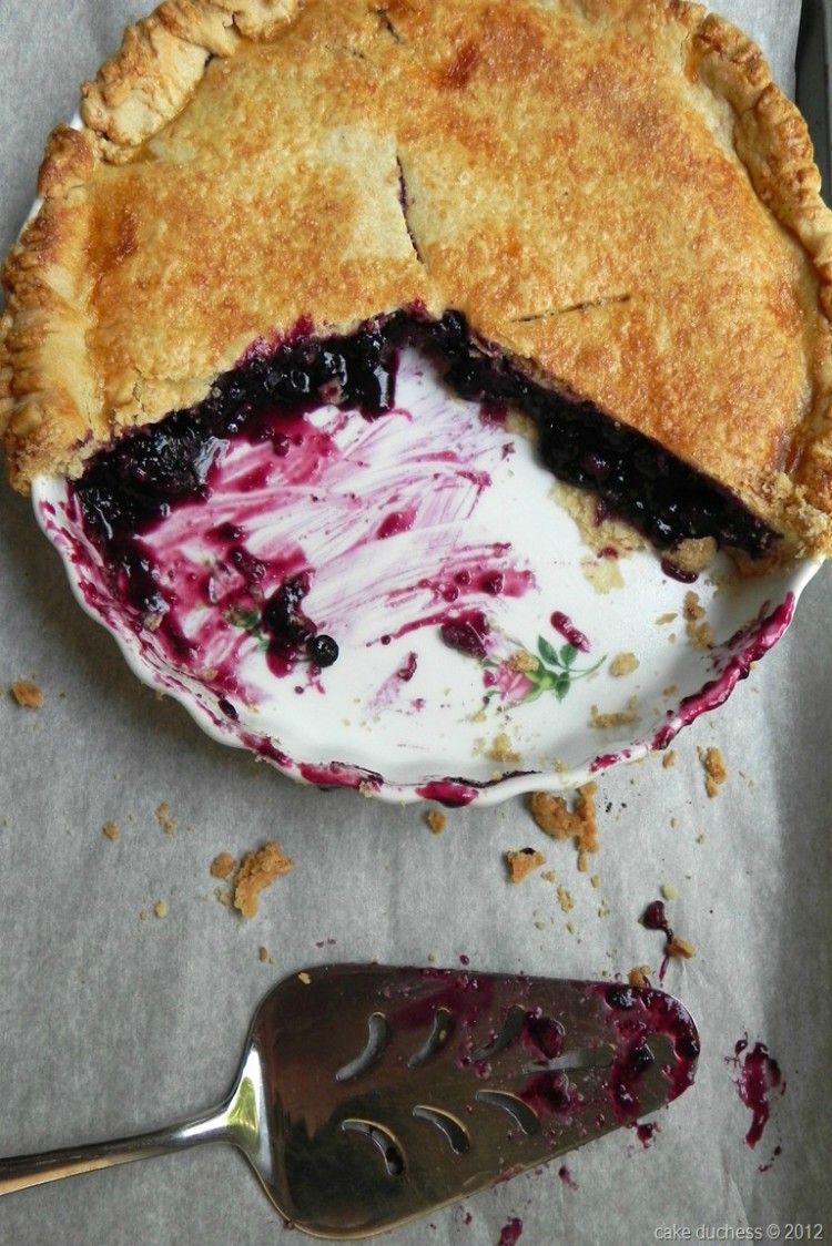 overhead image of blueberry pie sliced open on white dish