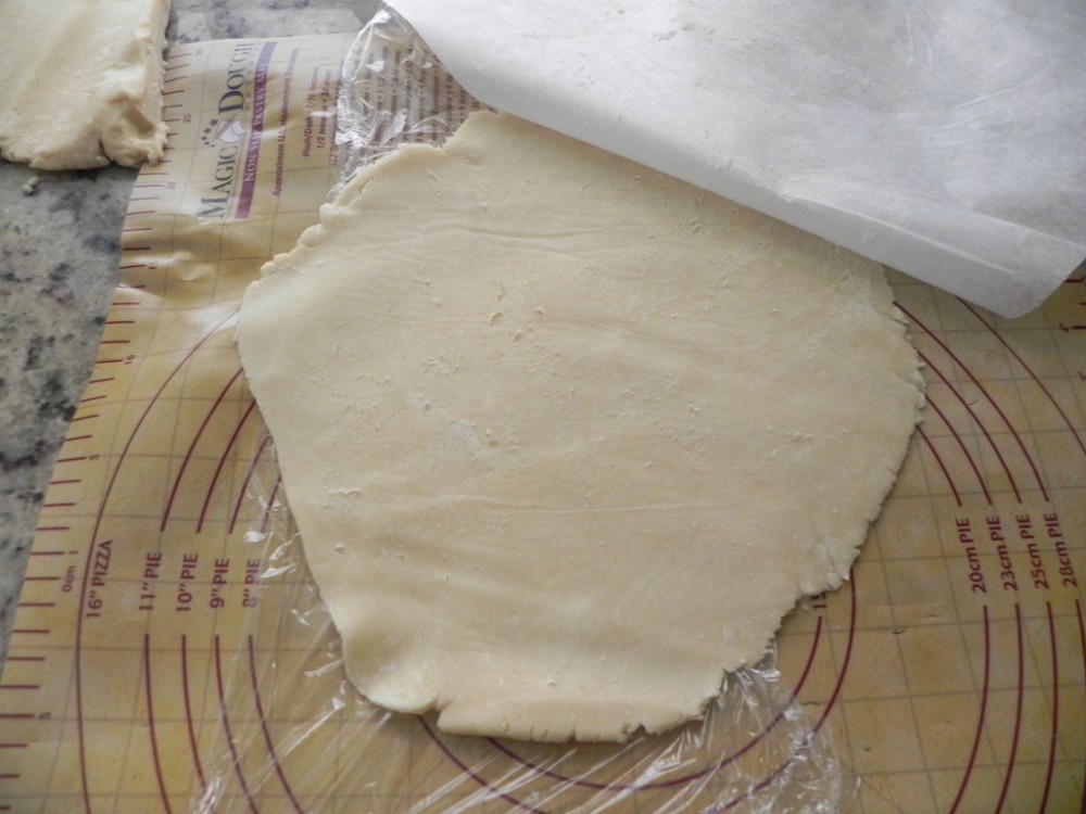 overhead image of dough rolling out on plastic wrap