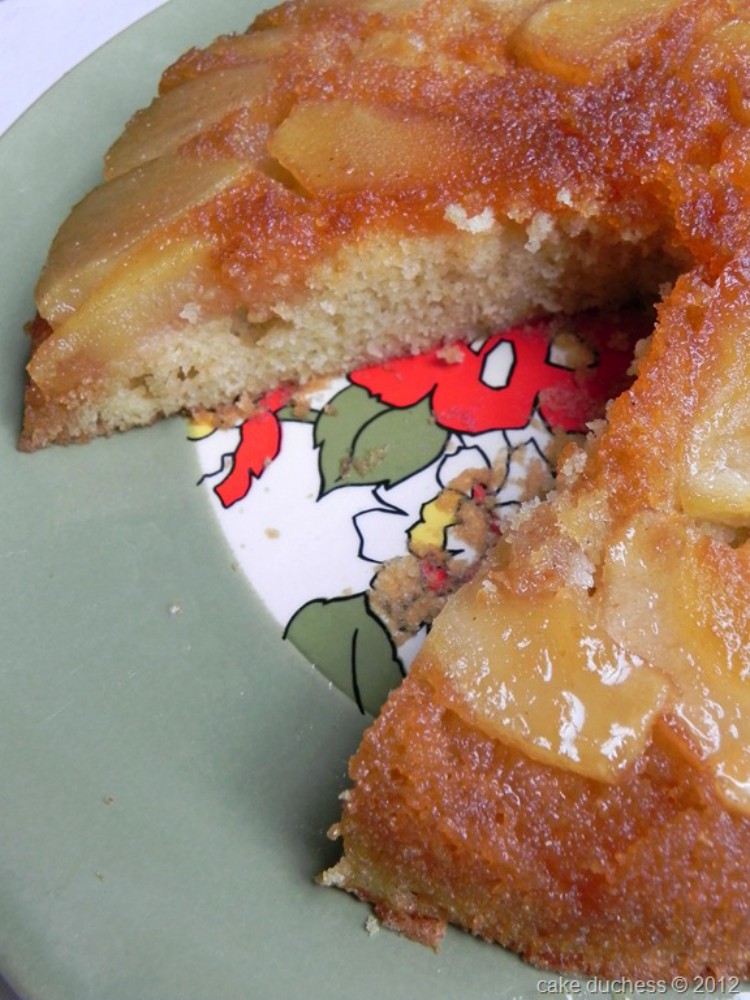 close up image of an upside down apple cake sliced on a green plate.