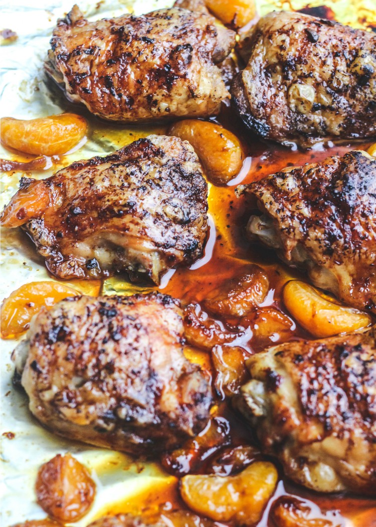 overhead image of baked chicken and oranges on a baking sheet