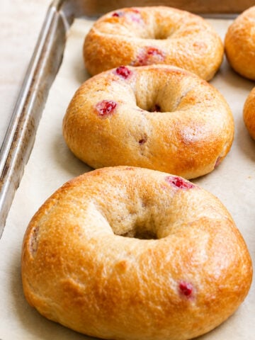 Three golden-brown Strawberry Bagels with visible bits of red fruit.