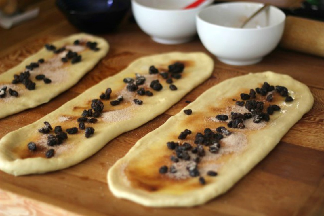 overhead image of strands of dough with cinnamon raisin filling