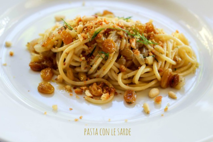 overhead image of spaghetti with raisins and pine nuts on white plate