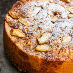 Italian vegan apple cake dusted with powdered sugar on a white cake stand