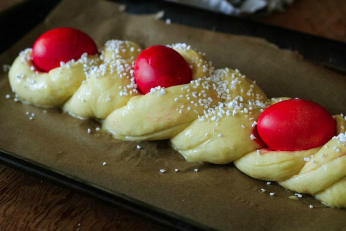 overhead image of greek easter bread with red eggs on baking sheet before baking