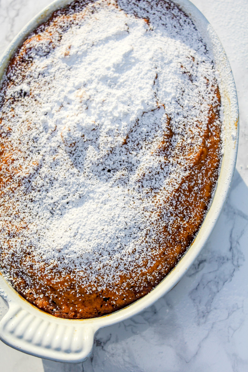 overhead image of cake with powdered sugar in a white baking dish