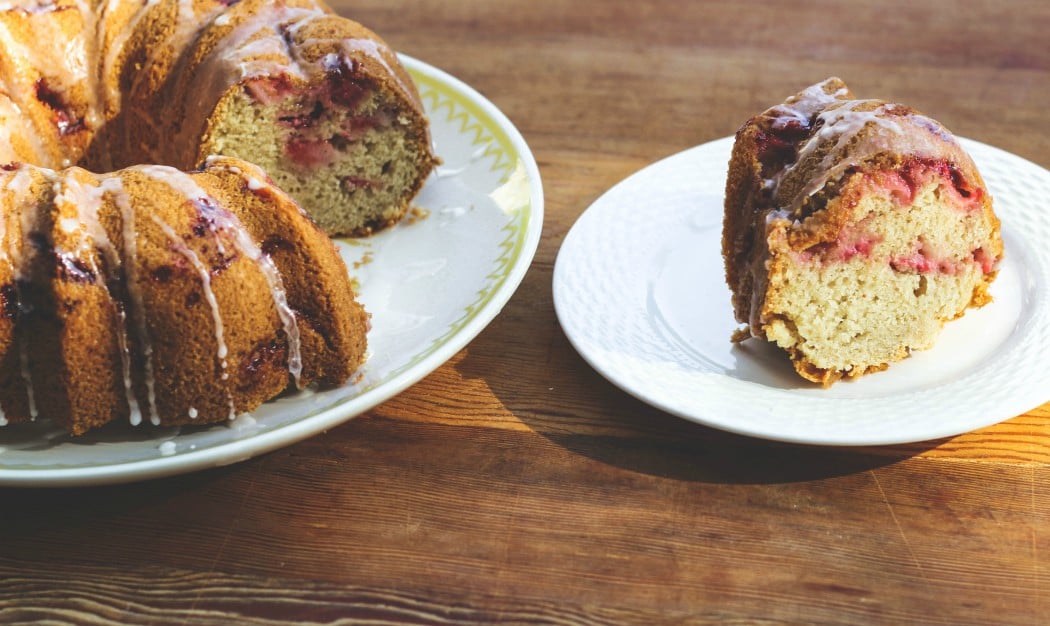 image of slice of fresh strawberry cake on plate next to larger bundt cake.