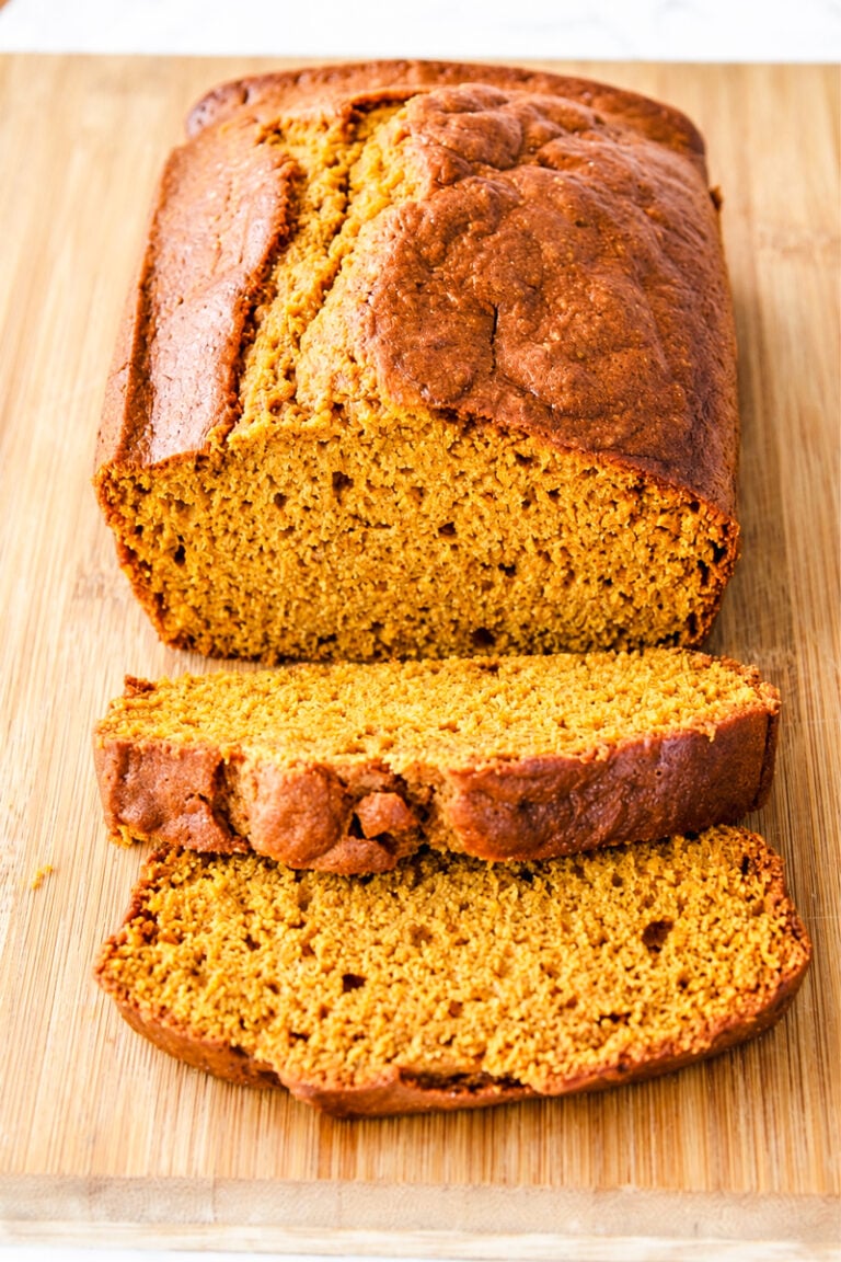A loaf of sliced pumpkin bread on a wooden cutting board.