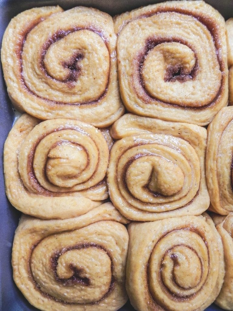 Overhead image of 9 cinnamon rolls in baking pans risen and ready to bake.