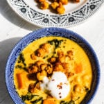 Close-up of creamy vegan chickpea stew with golden turmeric broth and kale