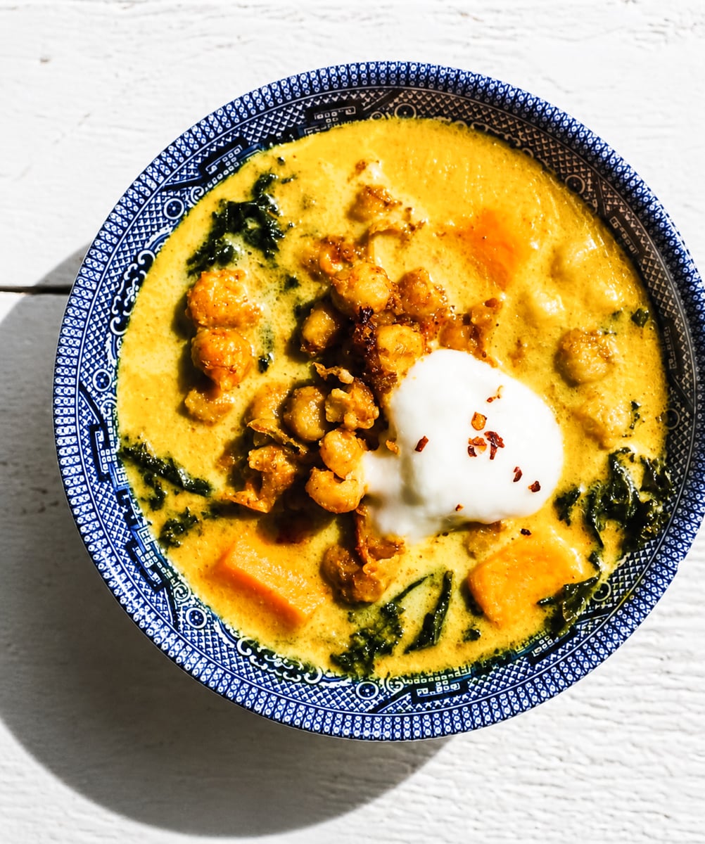 Close-up of creamy vegan chickpea stew with golden turmeric broth and kale
