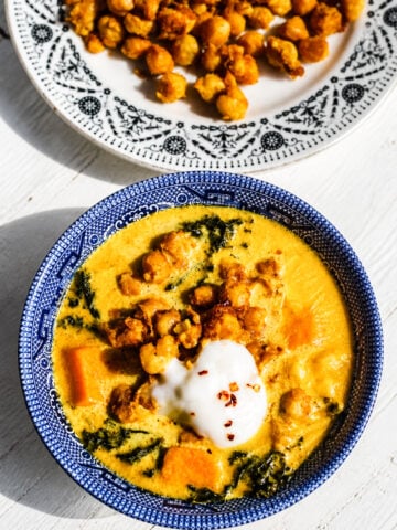 Close-up of creamy vegan chickpea stew with golden turmeric broth and kale