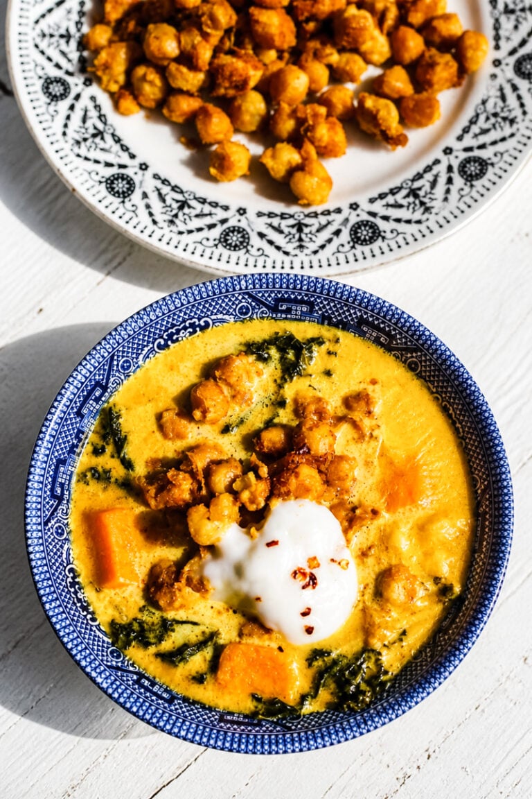 Close-up of creamy vegan chickpea stew with golden turmeric broth and kale