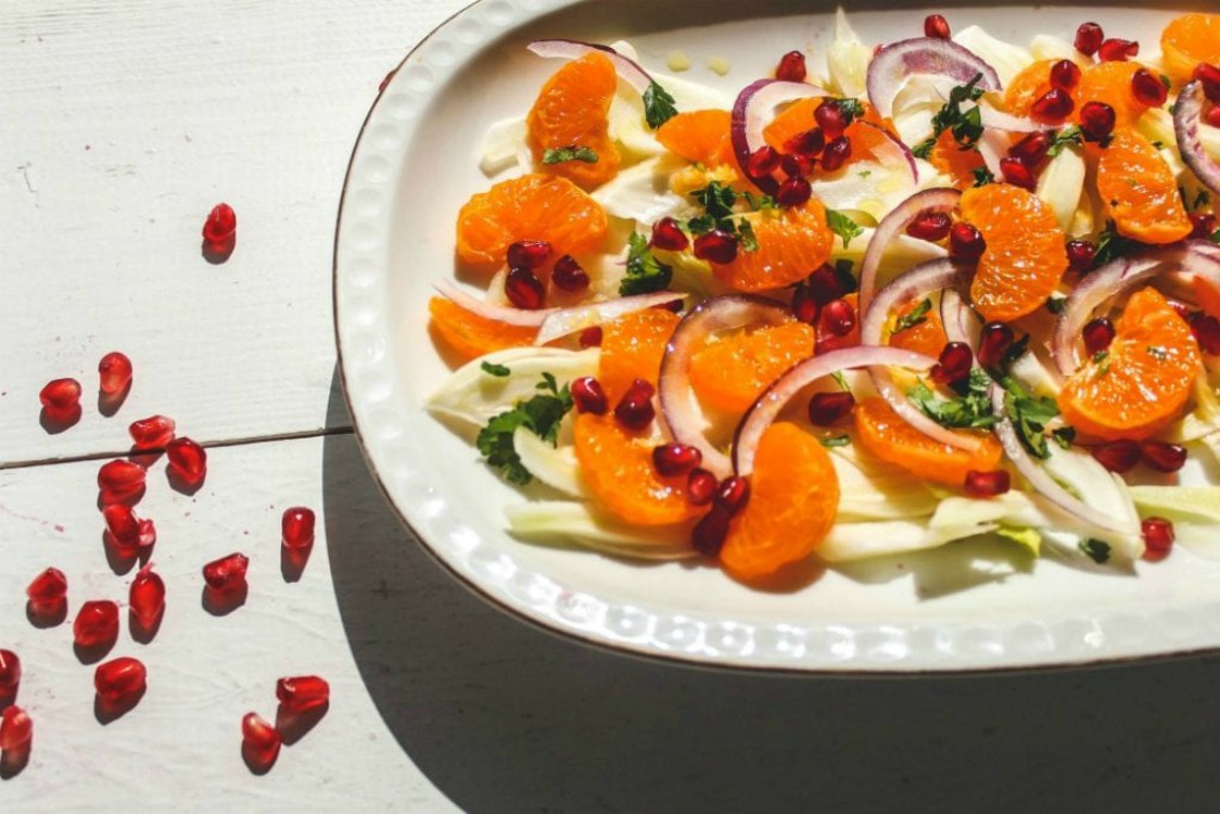 overhead image of salad with oranges and pomegranate arils on white plate