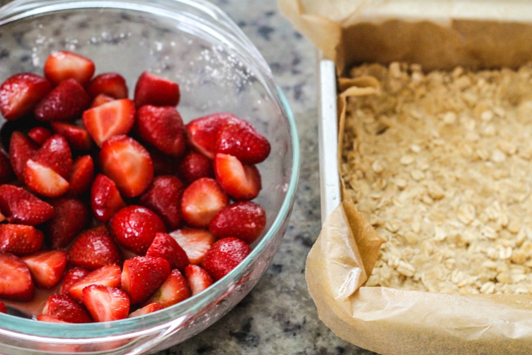 overhead image of strawberries in bowl and an oat crust