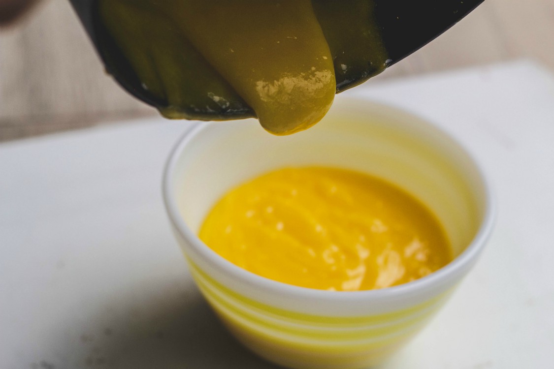 pouring lemon curd from saucepan to a bowl