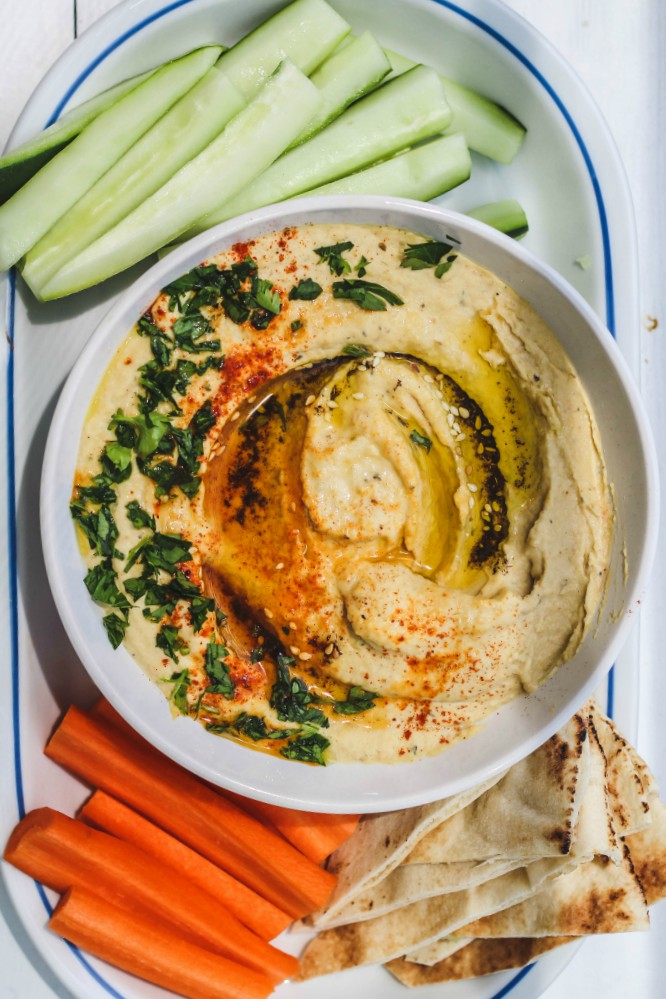 overhead image of hummus on a plate with vegetables