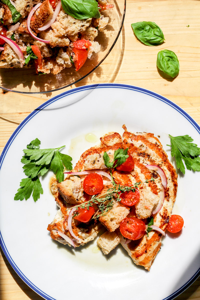 overhead image of chicken and tomatoes on a white and blue plate 