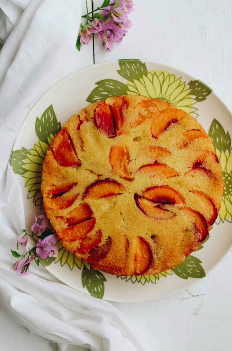 overhead image of a peach cake on a serving plate.