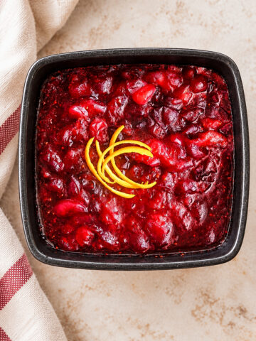 Square bowl of Italian cranberry sauce garnished with lemon zest.