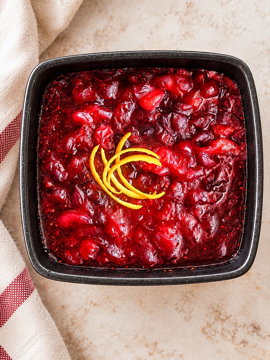 Square bowl of Italian cranberry sauce garnished with lemon zest.