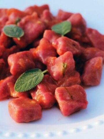 Beet gnocchi close up on white dish.