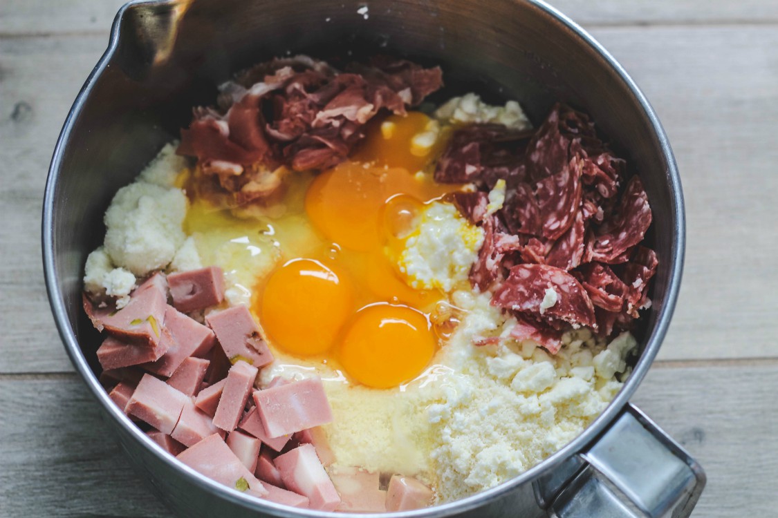 overhead image of metal bowl filled with eggs, meats and cheeses