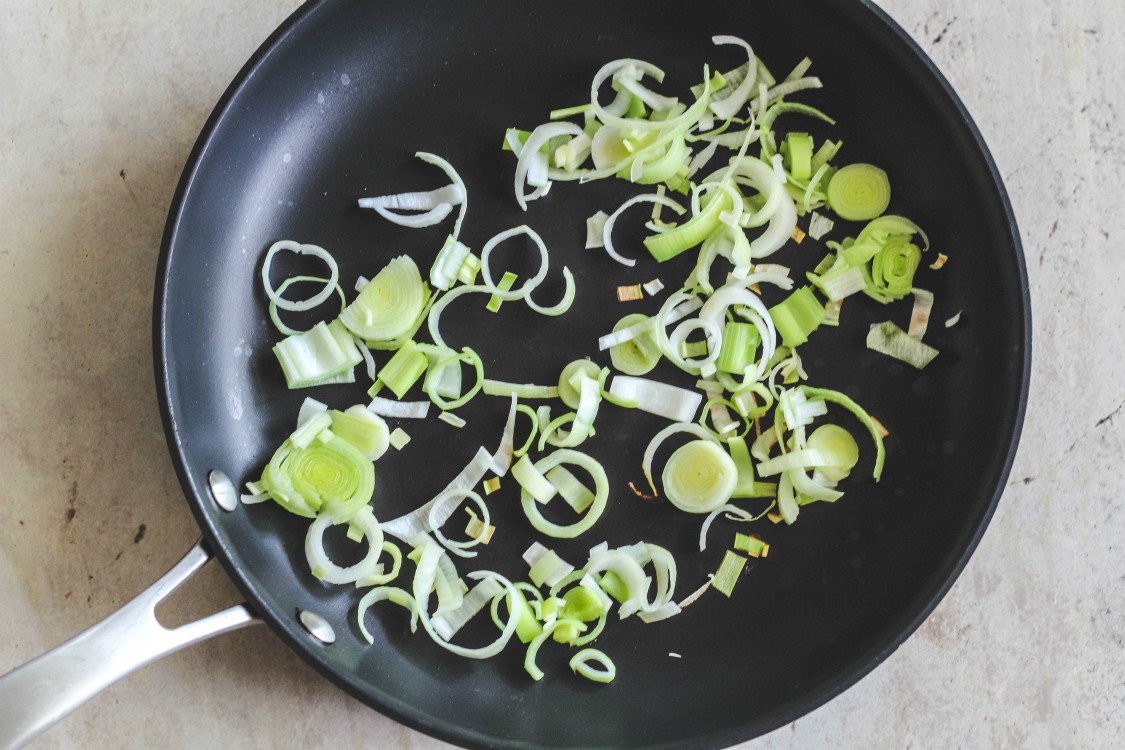 overhead image of cut up leeks in a saute pan