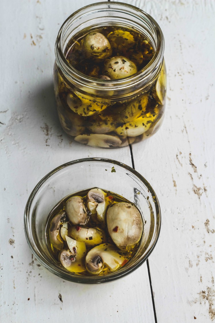 overhead image of marinated mushrooms in jars.