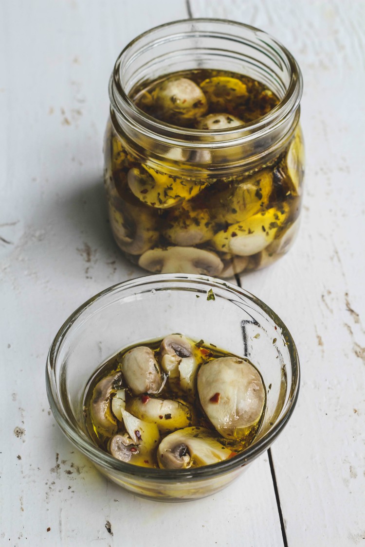 overhead image of easy marinated mushrooms in glass jars.