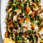 Vegan biryani salad in a large serving bowl with crispy fried shallots, cilantro, and colorful dried fruit