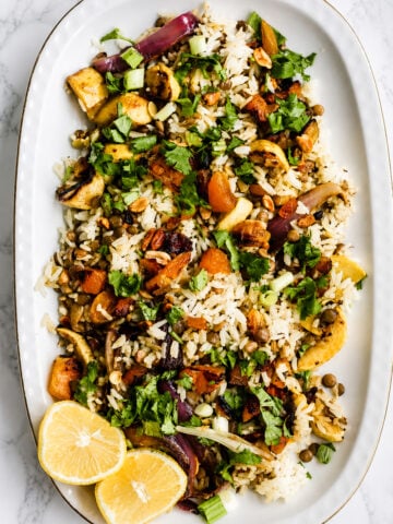 Vegan biryani salad in a large serving bowl with crispy fried shallots, cilantro, and colorful dried fruit