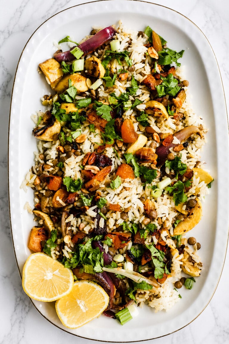 Vegan biryani salad in a large serving bowl with crispy fried shallots, cilantro, and colorful dried fruit