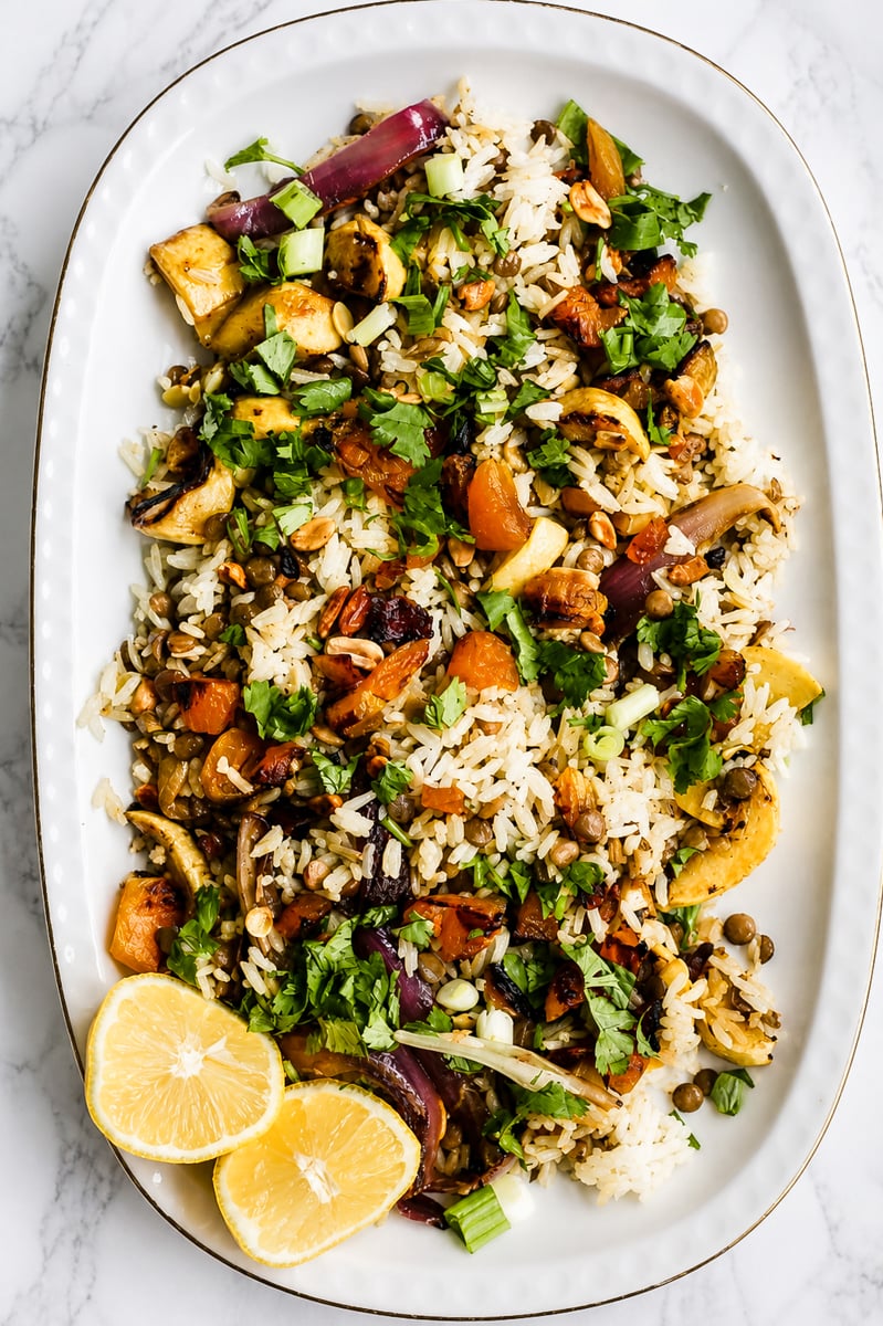 Vegan biryani salad in a large serving bowl with crispy fried shallots, cilantro, and colorful dried fruit