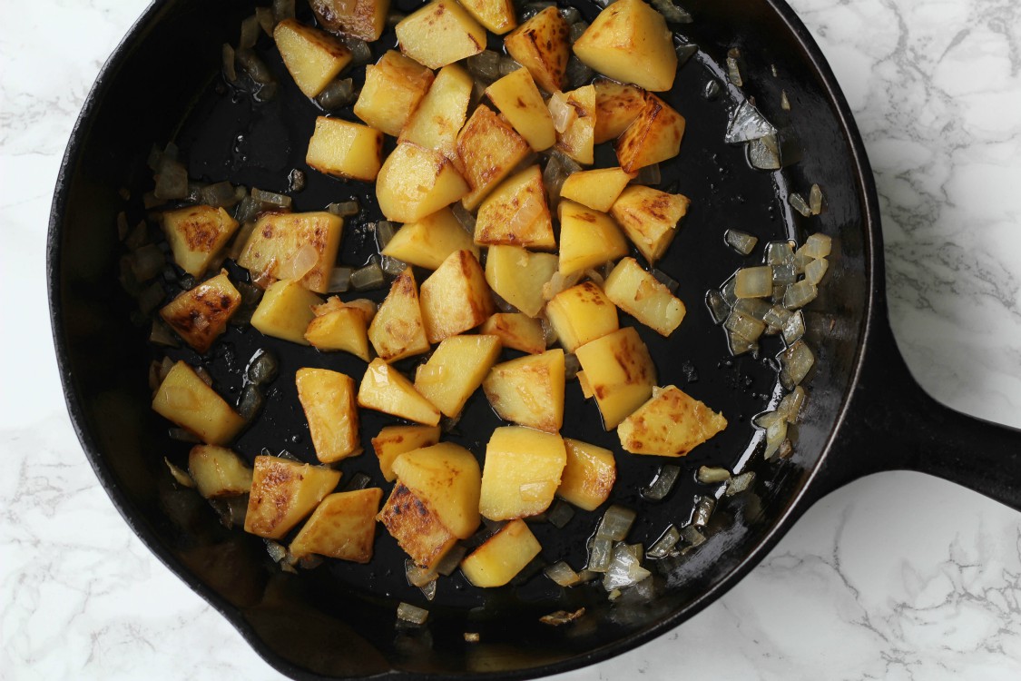 overhead image of potaotes and onions in a skillet