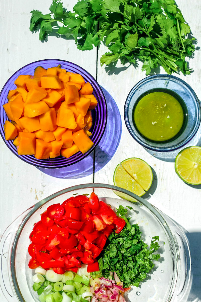 overhead image of ingredients to make mango salsa in a glass bowl with limes in background.